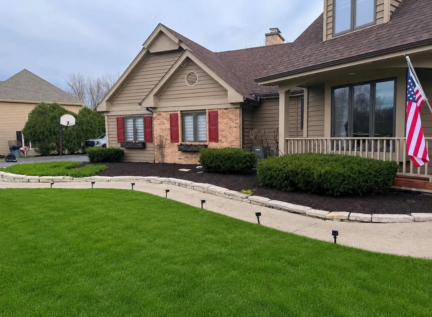 Freshly mulched front-yard landscaping with stone-edged walkway and manicured lawn