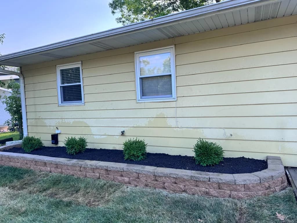 Finished stone retaining wall with mulch bed and shrubs